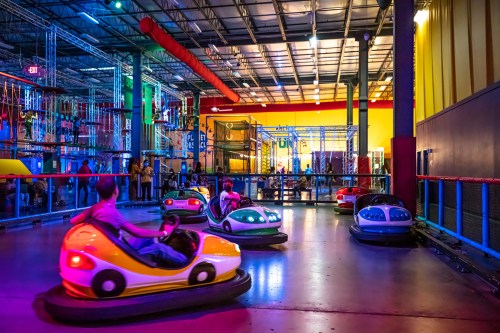 A vibrant indoor amusement park scene with colorful bumper cars and people enjoying the ride under bright lights.
