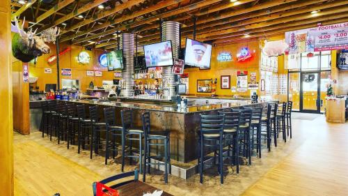 A spacious bar area with high stools, multiple TVs, and a rustic wooden ceiling, featuring sports memorabilia on the walls.