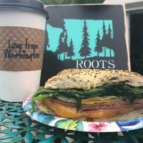 A sandwich with ham, cheese, and greens on a plate, next to a coffee cup labeled "Love from Washington."