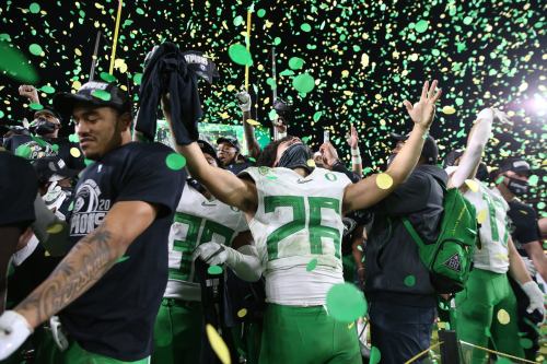A football team celebrates with confetti after a victory, players raising their arms in excitement.