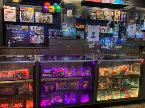 Colorful display of toys and games in a store, featuring illuminated bins and various merchandise on shelves.