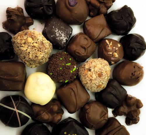 A variety of assorted chocolates in different shapes and textures, featuring dark, milk, and white chocolate.