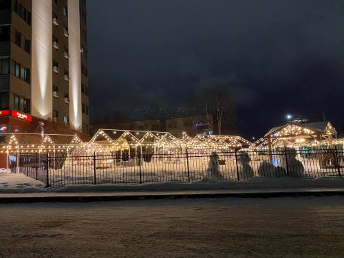 A snowy scene at night featuring illuminated structures and festive lights outside a building.