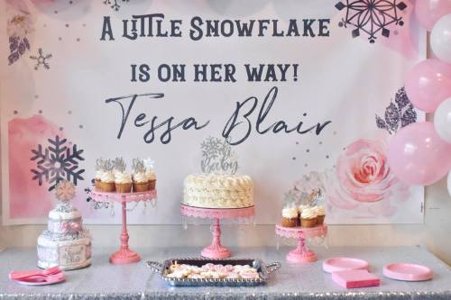 A festive dessert table with a banner, cake, cupcakes, and decorations for a baby shower themed "A Little Snowflake."