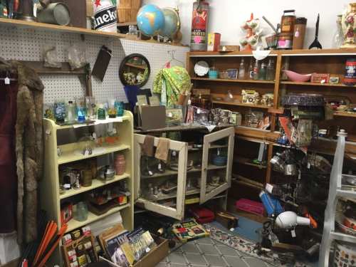 A cluttered antique shop filled with various vintage items, shelves, and displays of collectibles and decor.