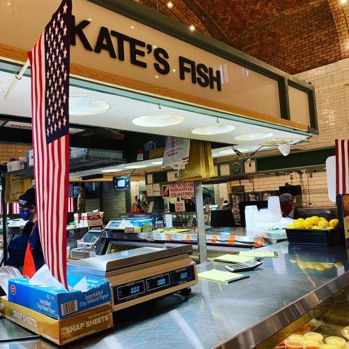 A seafood counter named "Kate's Fish" with an American flag and fresh lemons displayed.