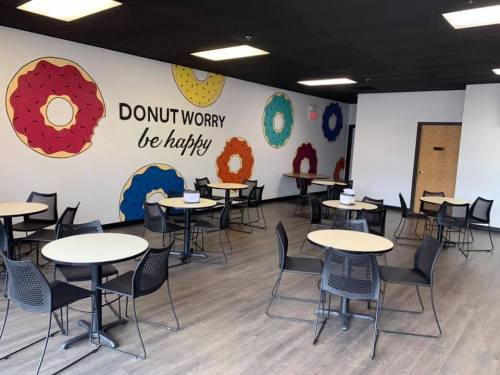 A bright cafe with donut-themed wall art and empty tables, creating a cheerful and inviting atmosphere.