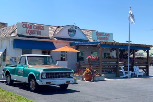 A vintage truck parked outside Matt's seafood restaurant, featuring a sign for crab cakes, lobster, and fried clams.
