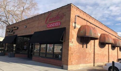 A brick building with a sign reading "Lorraine's Candies," featuring awnings and a clear blue sky.
