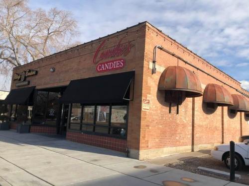 Exterior of a brick building with "Connie's Candies" sign, featuring large awnings and a sidewalk in front.