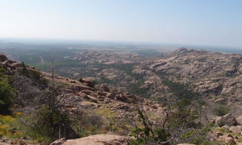 A panoramic view of rocky hills and valleys under a clear blue sky, showcasing a natural landscape.