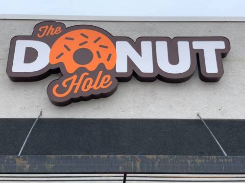 Sign for "The Donut Hole" featuring a donut graphic, displayed on a building exterior.