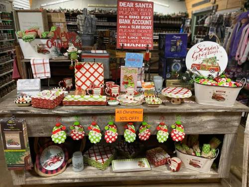 A festive display of Christmas decorations and gifts, featuring red and green items, with a "30% OFF" sign.