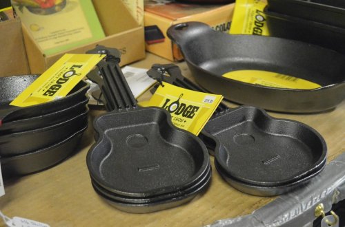 A collection of cast iron cookware, including small skillets and a larger pan, all with yellow price tags.