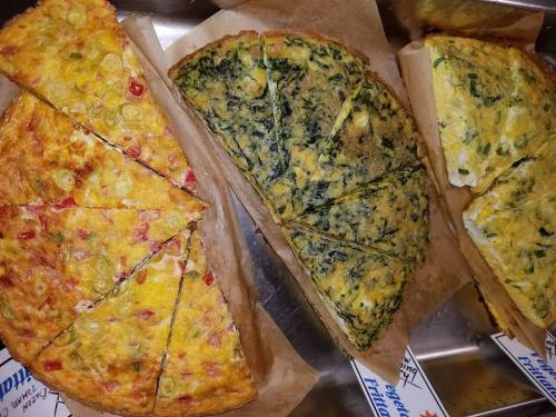 Three slices of frittata: one with vegetables, one with spinach, and one with mixed toppings, all on parchment paper.