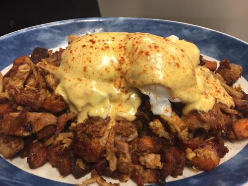 A plate of savory meat topped with creamy sauce and two poached eggs, garnished with paprika.