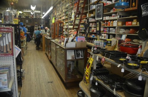 A vintage store interior with wooden shelves filled with various items, a checkout counter, and customers browsing.