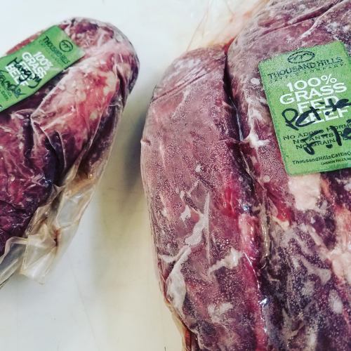 Two packages of frozen grass-fed beef, labeled "100% Grass Fed Beef" and "No Antibiotics or Hormones."