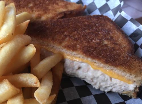 A golden-brown grilled cheese sandwich with melted cheese, served alongside crispy French fries.