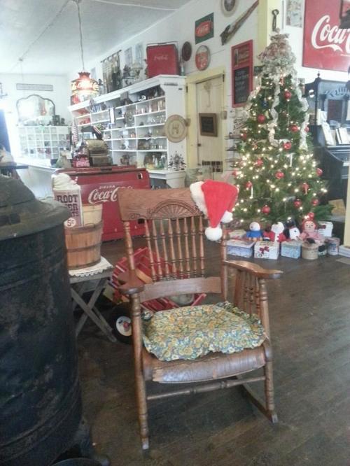 A cozy room decorated for the holidays, featuring a rocking chair with a Santa hat and a Christmas tree in the background.