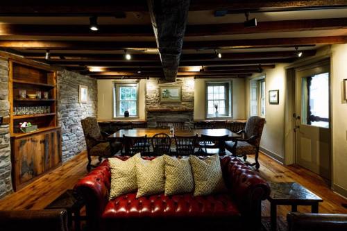 Cozy room with wooden beams, a leather sofa, and a large table surrounded by chairs, featuring stone and wood accents.
