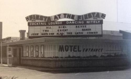 Black and white photo of a vintage motel with a marquee advertising a cocktail lounge and live music events.