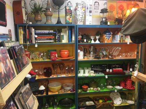 A colorful display of vintage items, including glassware, books, and decorative pieces on shelves.