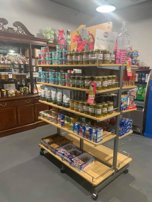 A display shelf filled with various jars, snacks, and packaged goods in a store setting.