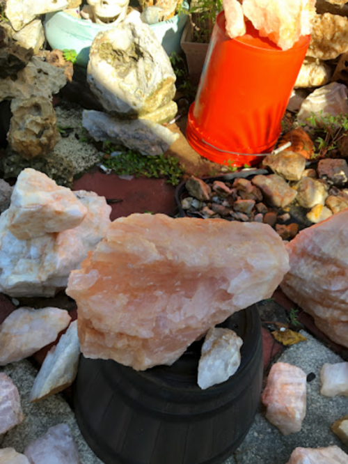 A collection of large pink crystals scattered around a red bucket in a garden setting.