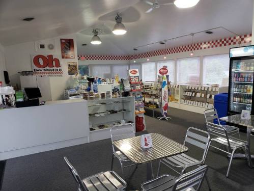 Interior of a cozy shop with a counter, display cases, and seating area, featuring snacks and drinks for sale.
