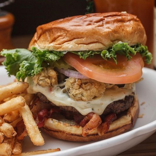 A juicy burger with lettuce, tomato, cheese, and crispy toppings, served with a side of golden fries.