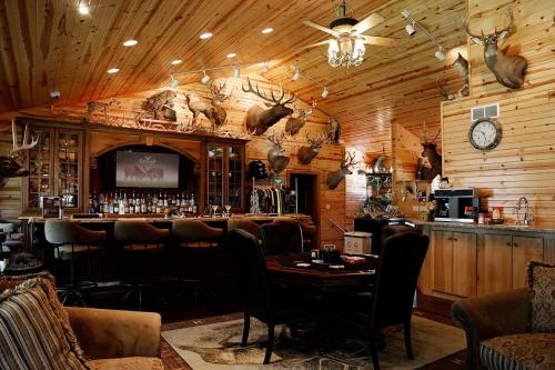 Cozy wooden bar area with mounted animal heads, plush seating, and a rustic decor featuring a clock and a bar counter.
