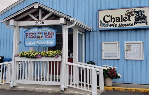 Exterior of Chalet Pie House with a sign for pies, flowers, and a welcoming entrance.