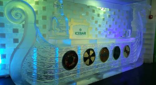 An ice bar shaped like a Viking ship, featuring colorful lighting and circular designs on the front.