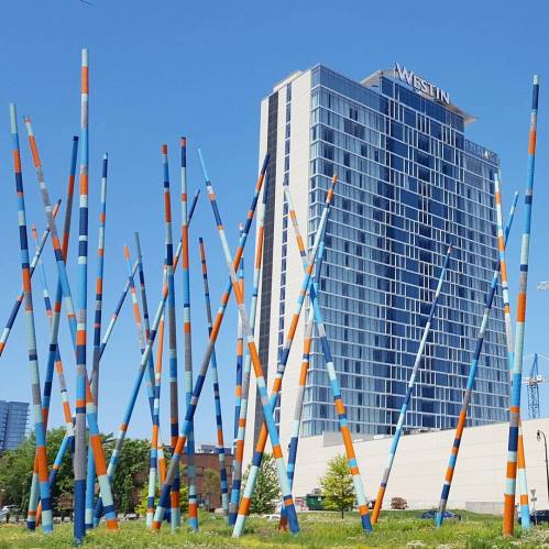 Colorful tall poles in front of a modern hotel building against a clear blue sky.