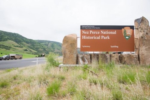 Sign for Nez Perce National Historical Park, surrounded by rocks and greenery, with a highway in the background.