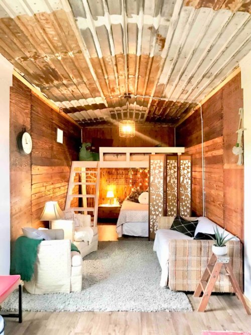 Cozy interior of a rustic room with wooden walls, a loft bed, and a warm, inviting atmosphere.