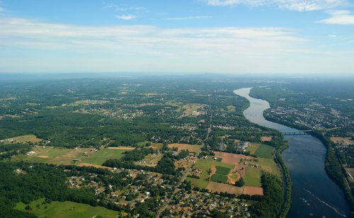 Aerial view of a river winding through green fields and small towns under a clear blue sky.