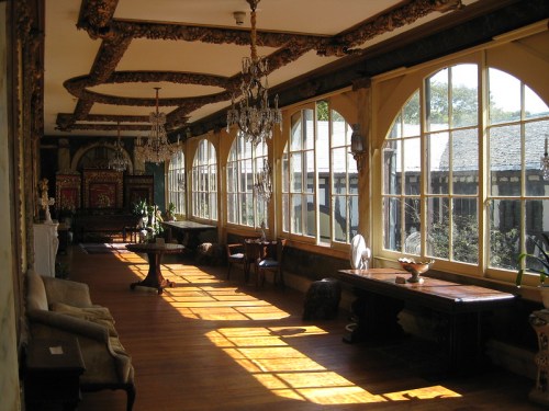 A sunlit room with large windows, ornate decor, and elegant furniture, creating a warm and inviting atmosphere.