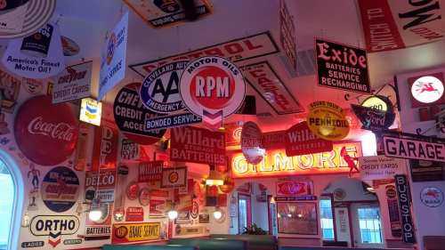 A vibrant diner interior filled with vintage automotive and gas station signs, creating a nostalgic atmosphere.