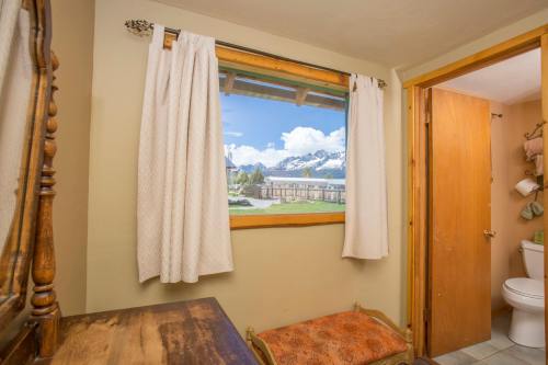 Cozy room with a window showcasing a mountain view, featuring a wooden dresser and a door leading to a bathroom.