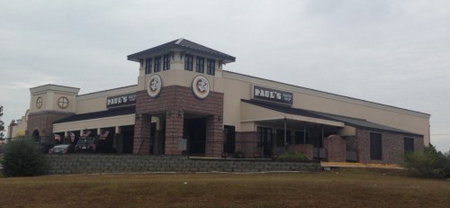 Exterior of a restaurant named "Paddy's," featuring a brick facade and a tower, with flags displayed outside.
