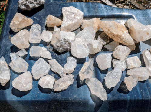 A collection of various clear and translucent quartz crystals scattered on a blue surface.