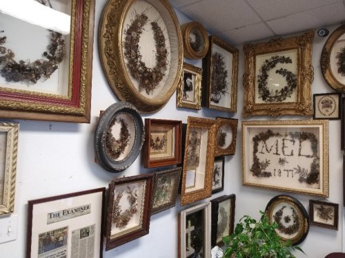 A wall adorned with various framed botanical wreaths and vintage photographs in ornate frames.