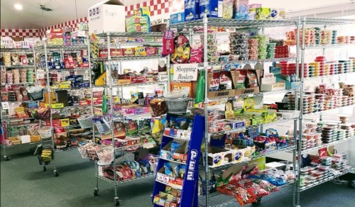 A colorful candy store filled with shelves of various sweets, snacks, and treats in organized displays.