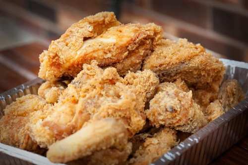 A close-up of a tray filled with crispy, golden-brown fried chicken pieces.