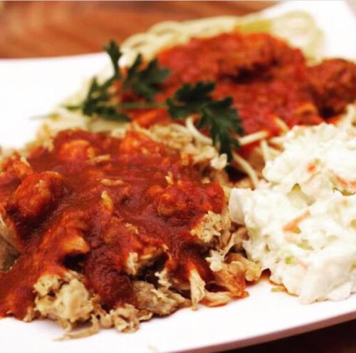 A plate of spaghetti with meatballs in marinara sauce, accompanied by coleslaw and garnished with parsley.