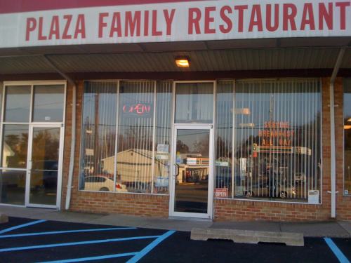Exterior of Plaza Family Restaurant with "OPEN" sign, large windows, and a parking lot in front.