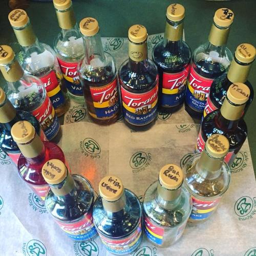 A collection of Torani syrup bottles arranged in a circle on a table, with various flavors labeled on the caps.