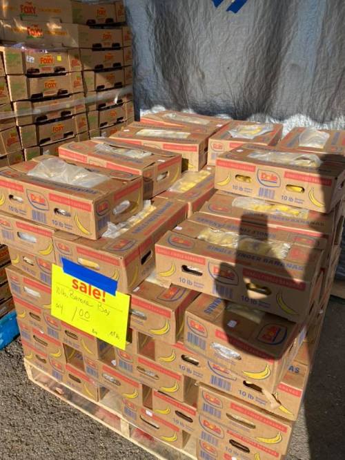 A stack of banana boxes for sale, with a bright yellow sign indicating a price of $100.